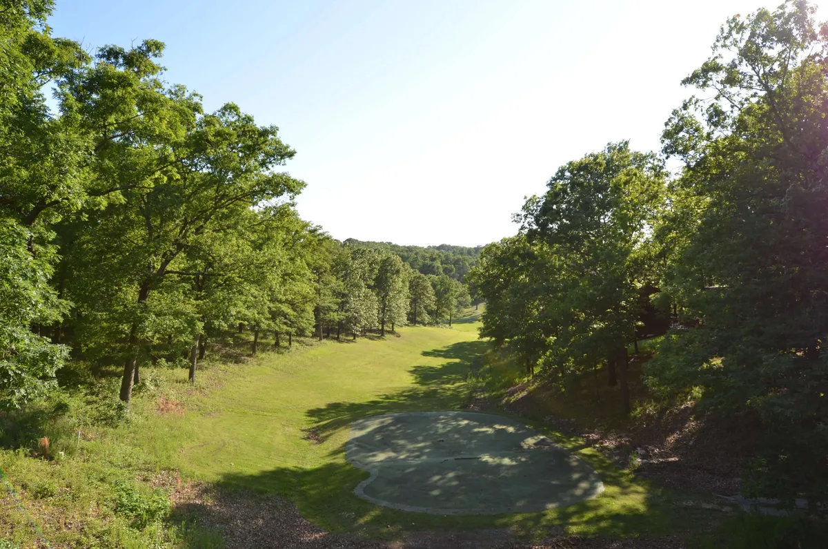 An expansive green area with a golf green, lush trees, and wide open space offers a setting for peaceful activities like golfing, picnics, and nature walks. The calm atmosphere highlights the tranquility available just beyond the event scene.