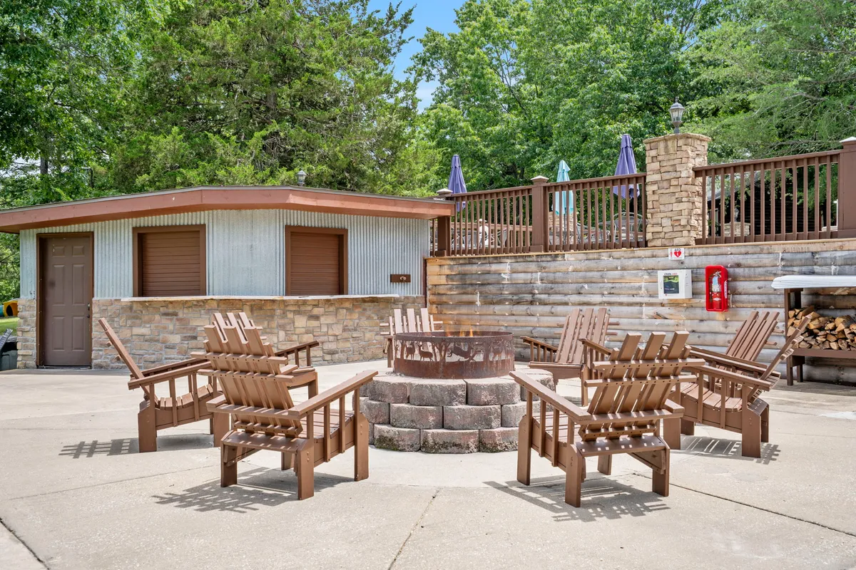 A cozy community fire pit surrounded by Adirondack chairs and lush greenery. The patio setting invites social gatherings and relaxed evenings under the stars.