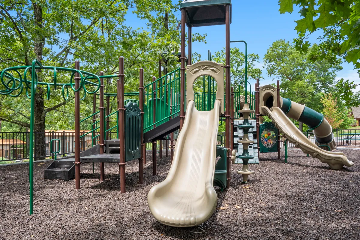 A colorful playground structure with slides and climbing frames sits in a grassy area, inviting children for energetic play. The scene is lively and ideal for families with kids looking for outdoor recreation.